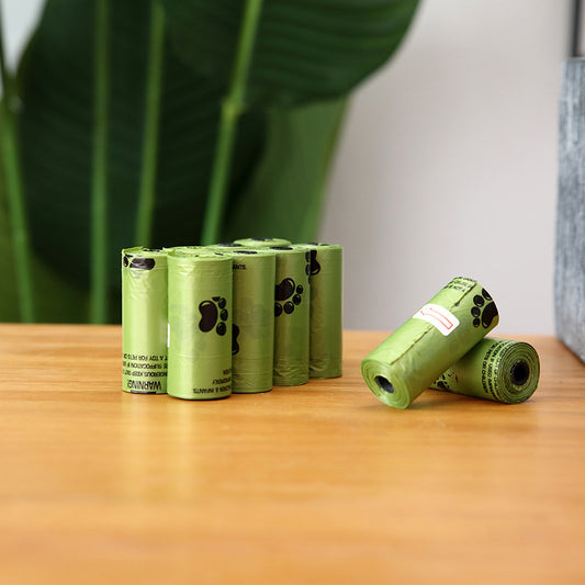 Green pet waste bags with paw prints on a wooden surface